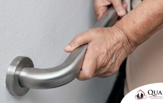 An older adult uses a grab bar representing one of the home modifications that is helpful for fall prevention for elderly adults.